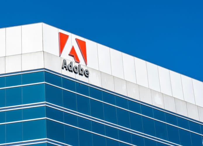 Imagem mostra o topo de um prédio comercial com o logotipo da Adobe na fachada