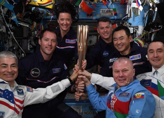 Imagem dos astronautas da ISS com uma tocha olímpica improvisada