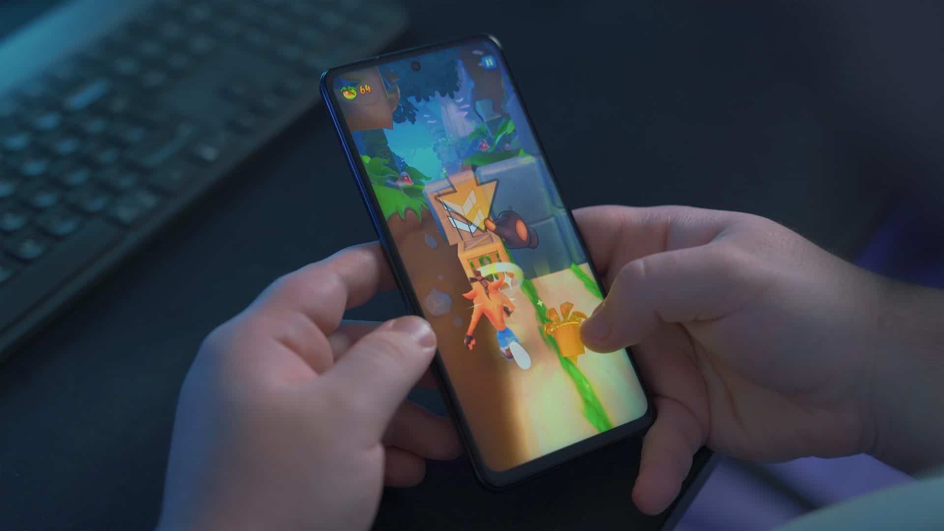 App Google Play Games terá novos recursos no Android 12. Imagem mostra mãos jogando em smartphone disposto na vertical. Imagem: Onur Binay/Unsplash
