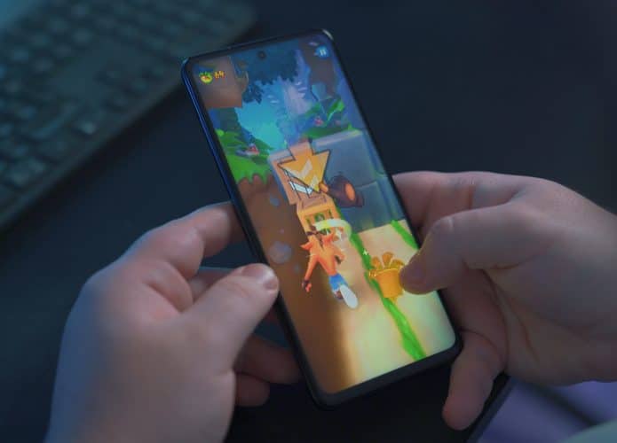App Google Play Games terá novos recursos no Android 12. Imagem mostra mãos jogando em smartphone disposto na vertical. Imagem: Onur Binay/Unsplash