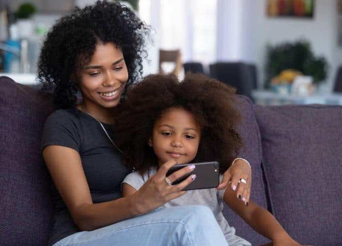 Mãe e criança assistem vídeo no celular