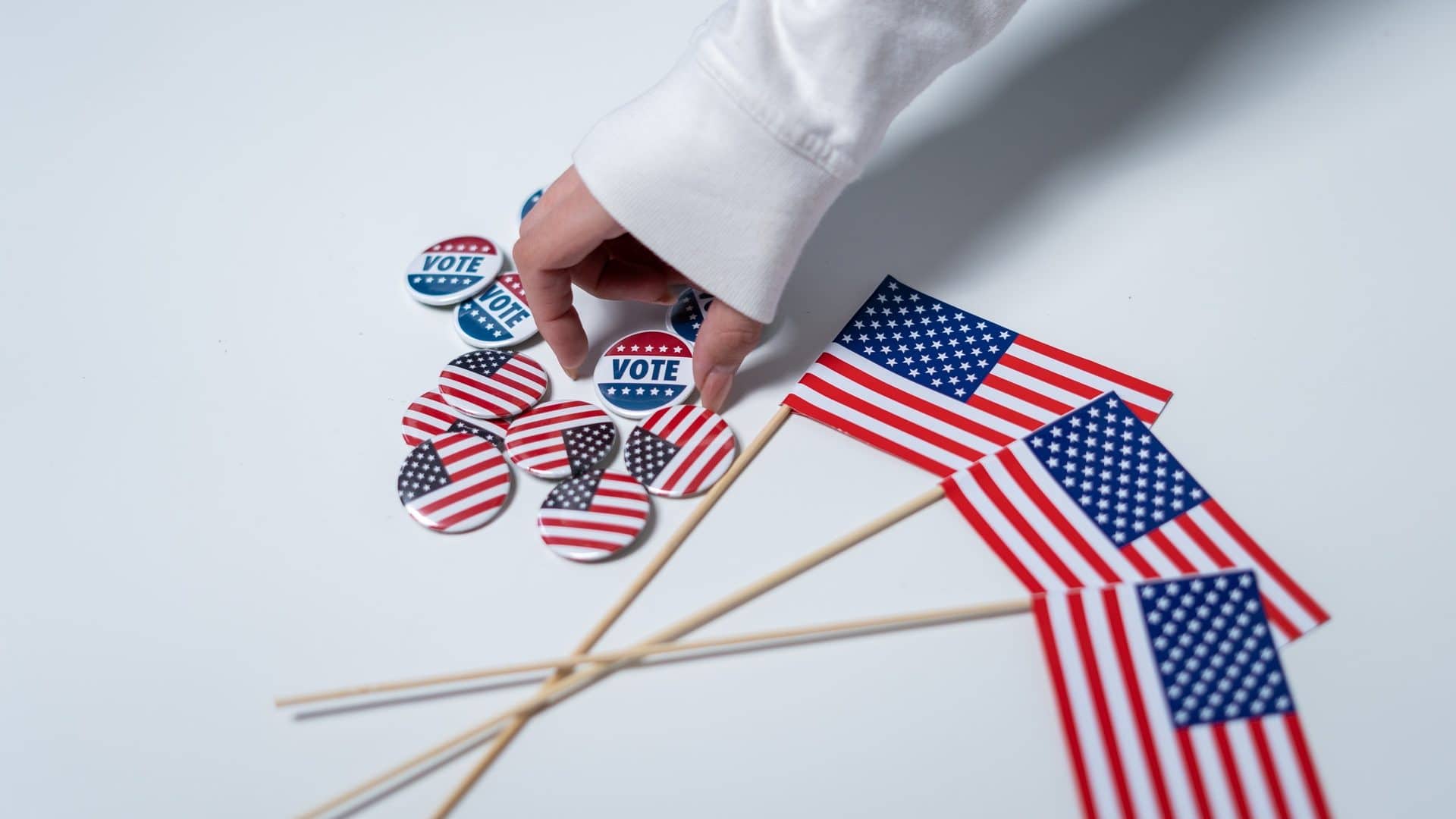 mão de moça pegando um botton que ilustra as eleições nos EUA e o sistema eleitoral americano