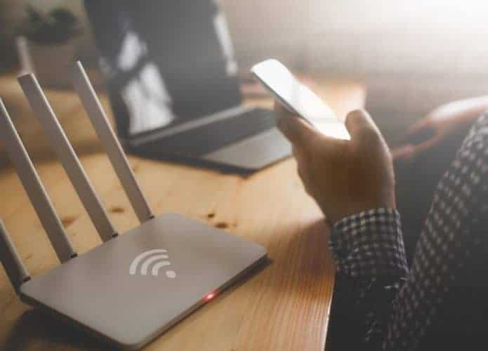 Um roteador de internet sem fio e um homem usando um smartphone