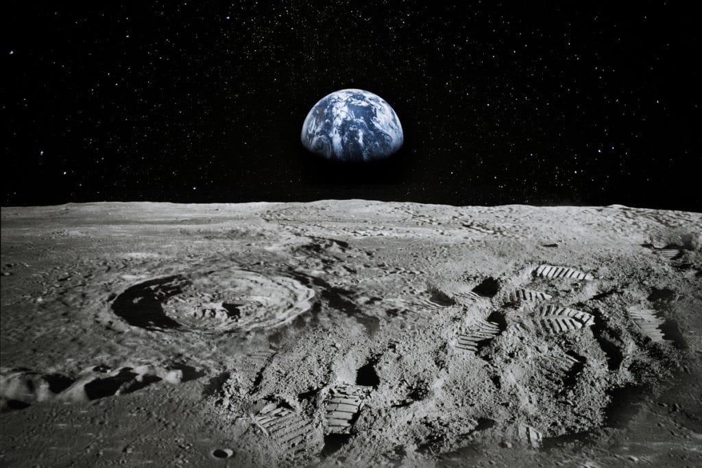 Imagem mostra a superfície da Lua, com a Terra vista ao fundo. Novo estudo da Nasa argumenta que a Lua pode esconder água nas sombras de suas crateras