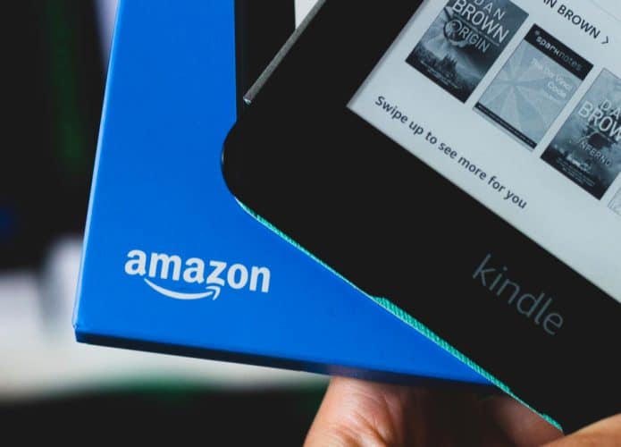 Imagem mostra um Kindle sendo retirado de uma caixa com o logotipo da Amazon