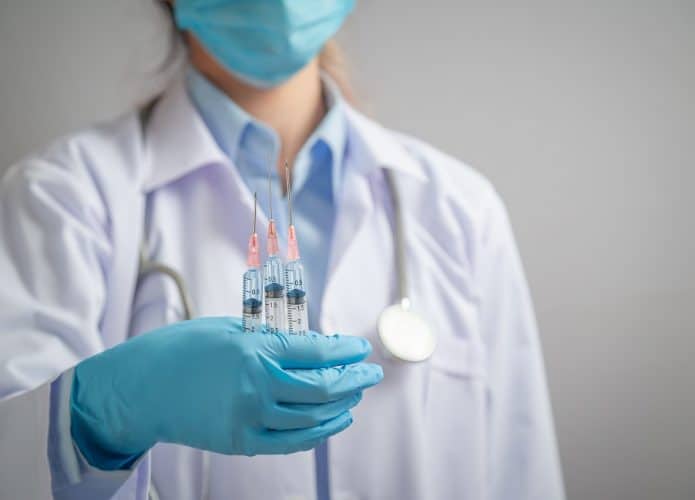 médica segura três doses de vacina contra Covid-19