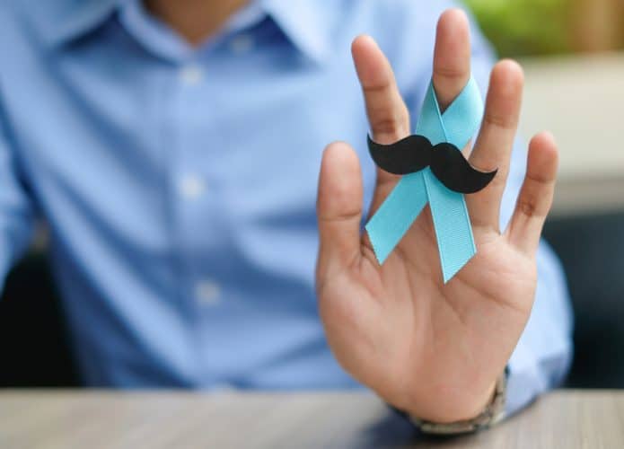 Homem segurando um laço azul com bigodes