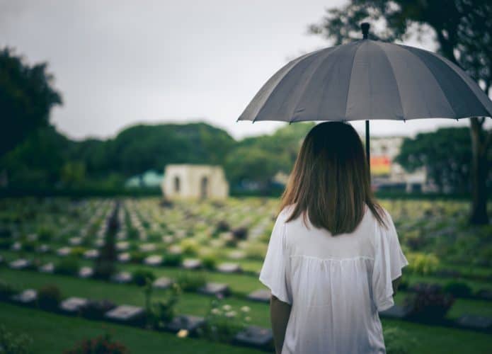 Mulher com um guarda-chuva olhando para um cemitério