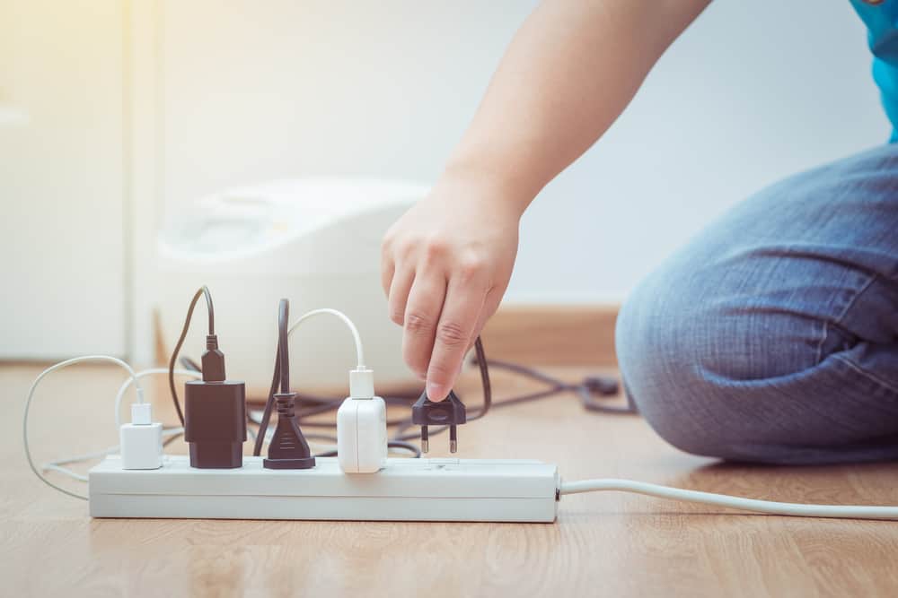 Mão desconectando plugue da tomada para economizar energia