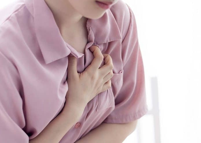 Mulher aperta o peito indicando doenças cardiovascular