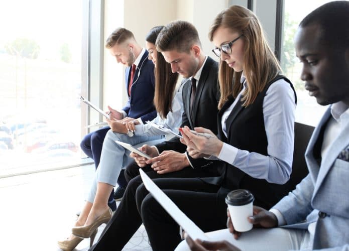 Imagem mostra candidatos à entrevista de emprego esperando sentados, um ao lado dos outros