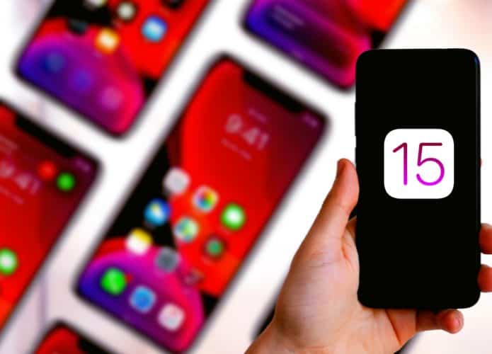 Imagem mostra, ao fundo, diversos iPhones; à frente, há uma mão segurando um aparelho da Apple que exibe o ícone do iOS 15 na tela