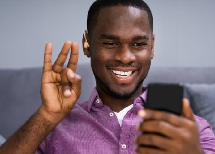 Homem negro surdo conversa no celular usando linguagem de sinais