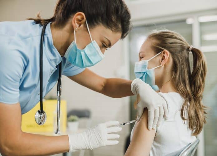 Profissional da saúde aplicando a vacina em adolescente