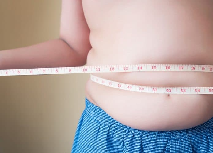 Criança com uma fita métrica medindo a barriga