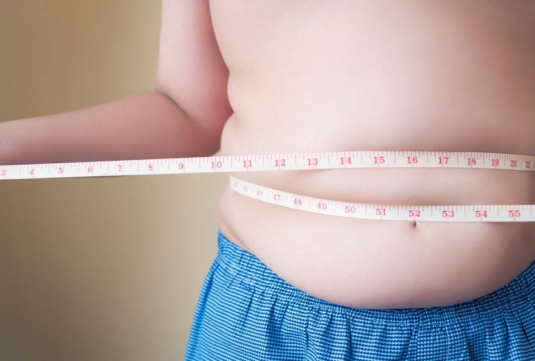 Criança com uma fita métrica medindo a barriga