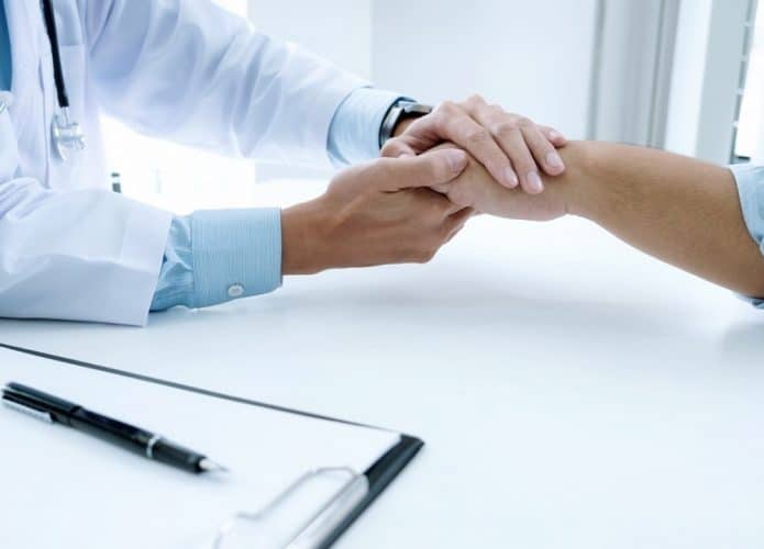Médico com a mão sobre a mão do paciente