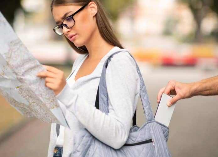 mulher lendo mapa enquanto celular é roubado da bolsa