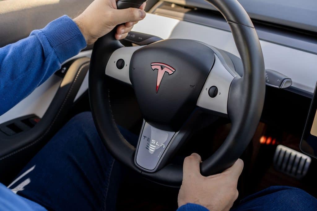 Homem segurando volante de um automóvel da Tesla