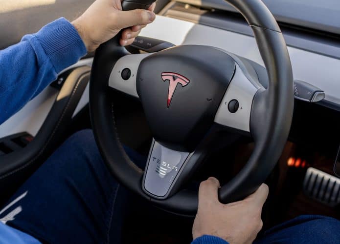 Homem segurando volante de um automóvel da Tesla