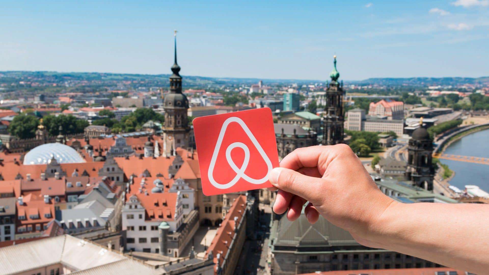 Logo do Airbnb com paisagem de cidade ao fundo