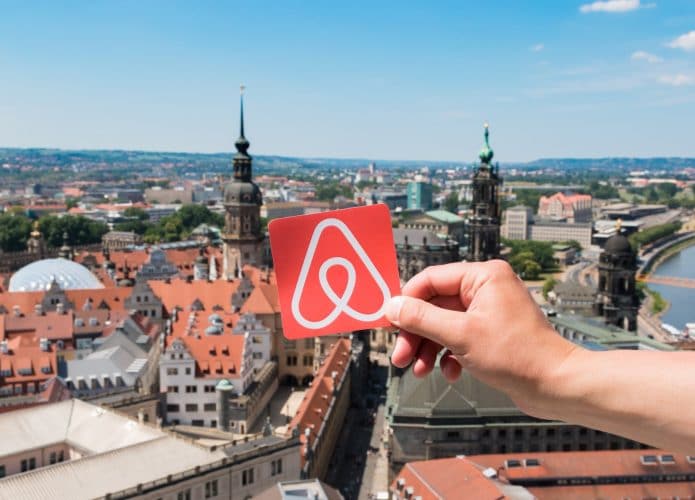 Logo do Airbnb com paisagem de cidade ao fundo