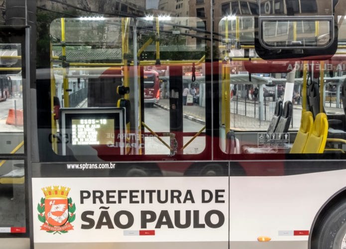 Imagem mostra a lateral externa de um ônibus da capital paulista, adesivado com os dizeres Prefeitura de São Paulo e o brasão da prefeitura.