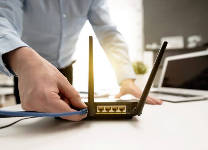 Homem conectando um cabo de rede em um roteador de internet sem fio
