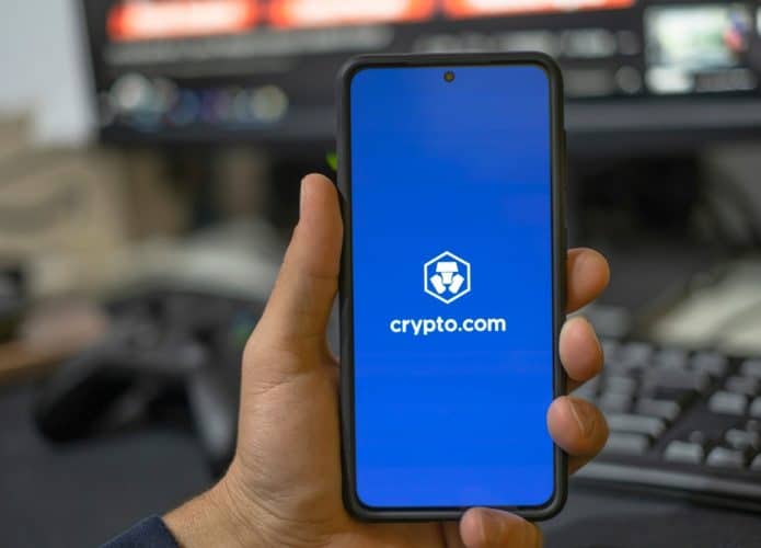 Homem usando o aplicativo da corretora de criptomoedas Crypto.com em um smartphone