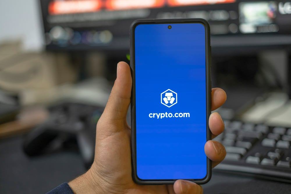 Homem usando o aplicativo da corretora de criptomoedas Crypto.com em um smartphone