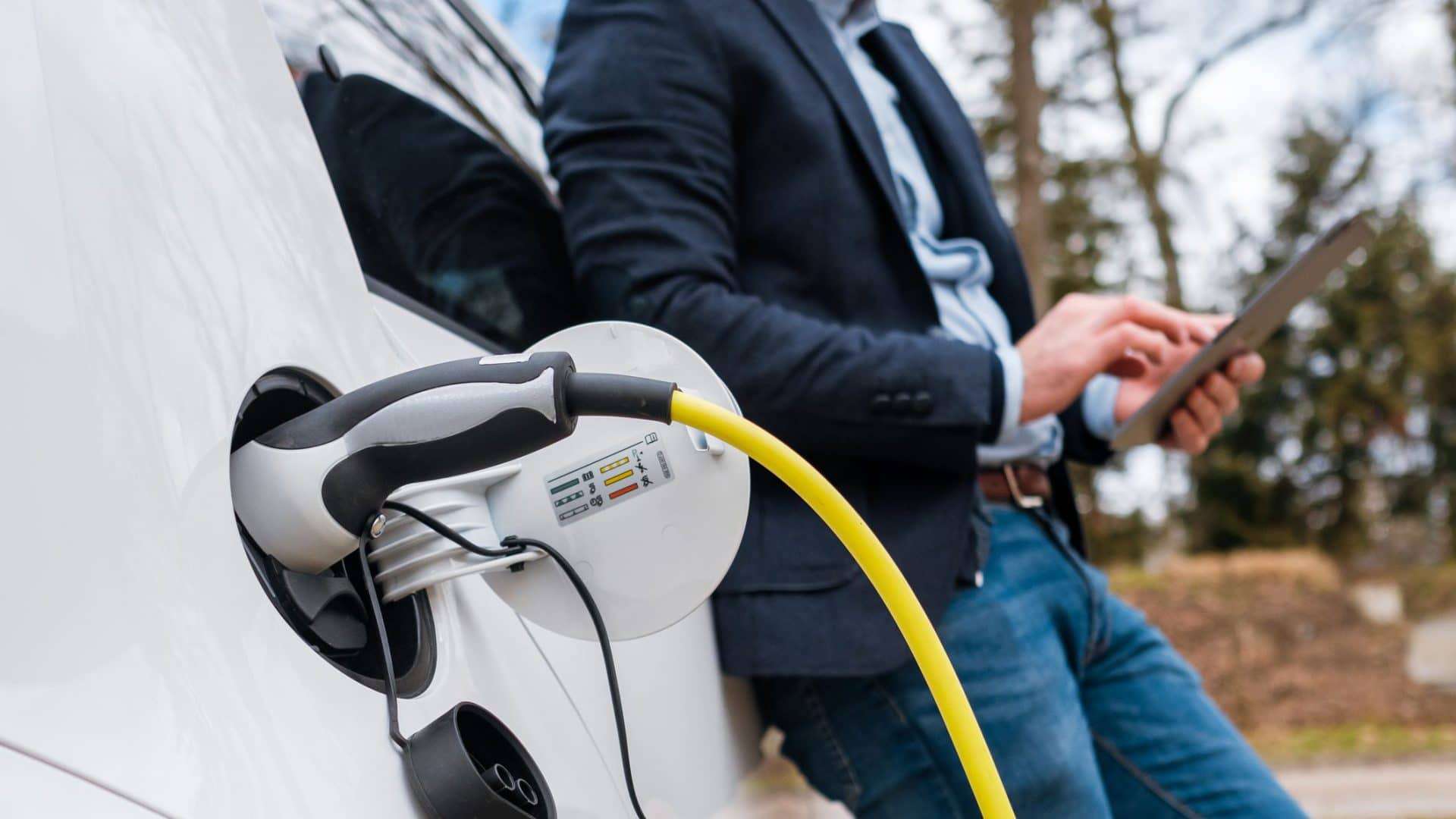 pessoa calculando os custos enquanto carrega seu veículo elétrico