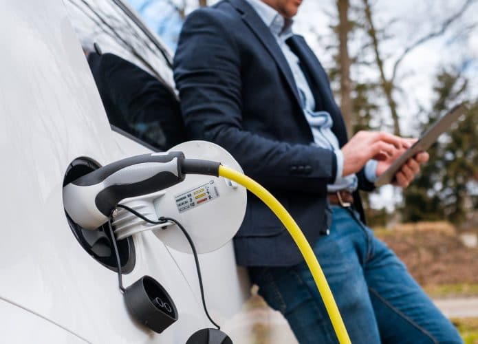 pessoa calculando os custos enquanto carrega seu veículo elétrico