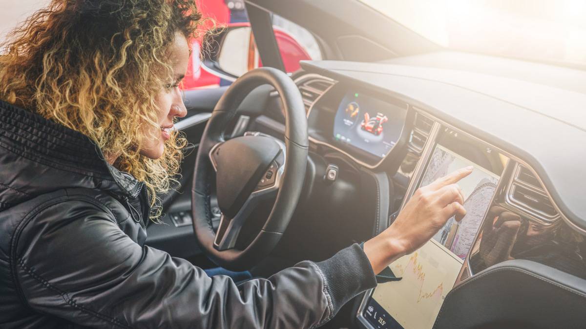 Mulher usando touchscreen em Tesla, que pode permitir jogos