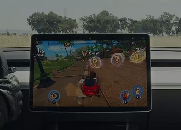 jogo de videogame em uma tela central na cabine de um carro da Tesla e com o motorista dirigindo