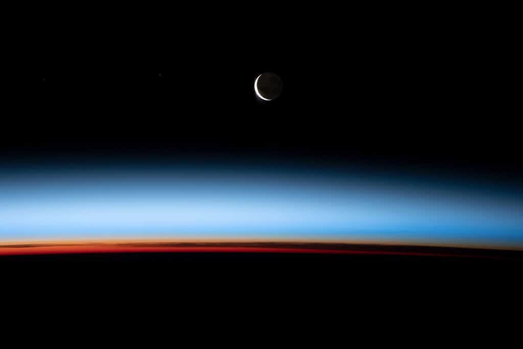 Lua crescente sobre um pôr do sol na Terra