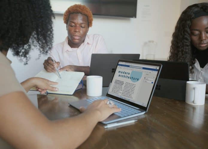 Pessoas trabalhando juntas em relatório no Word