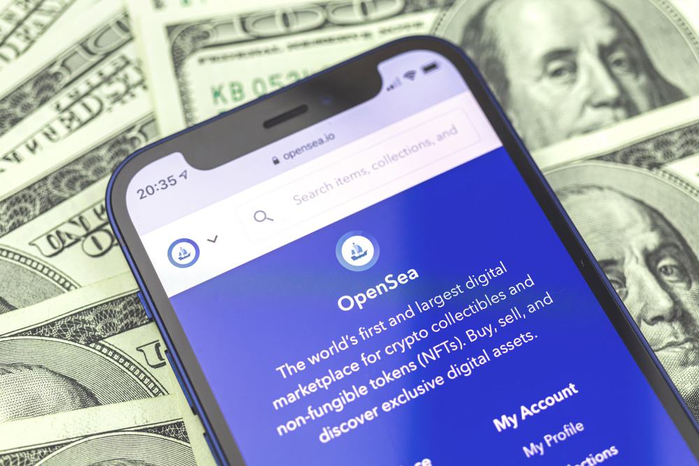 Site da OpenSea, o maior marketplace do mundo, aberto na tela de um celular com notas de dólares ao fundo