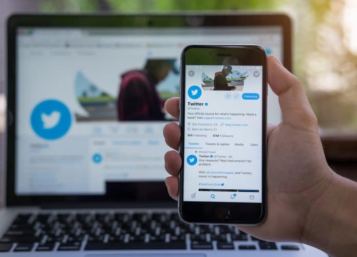 Pessoa segurando um iPhone com o aplicativo do Twitte exibido na tela. O Twitter é um serviço online de mídia social