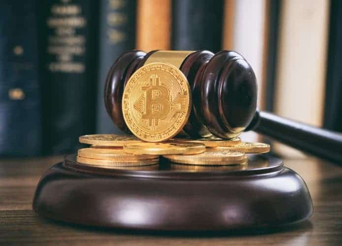 Moedas da criptomoeda Bitcoin com um martelo de tribunal sobre uma mesa de madeira.