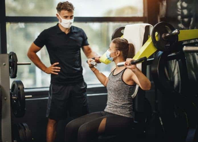 Pessoas treinando na academia com máscara