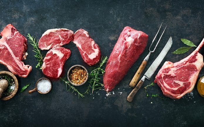 Vários tipos de carne bovina e temperos em cima de uma bancada preta