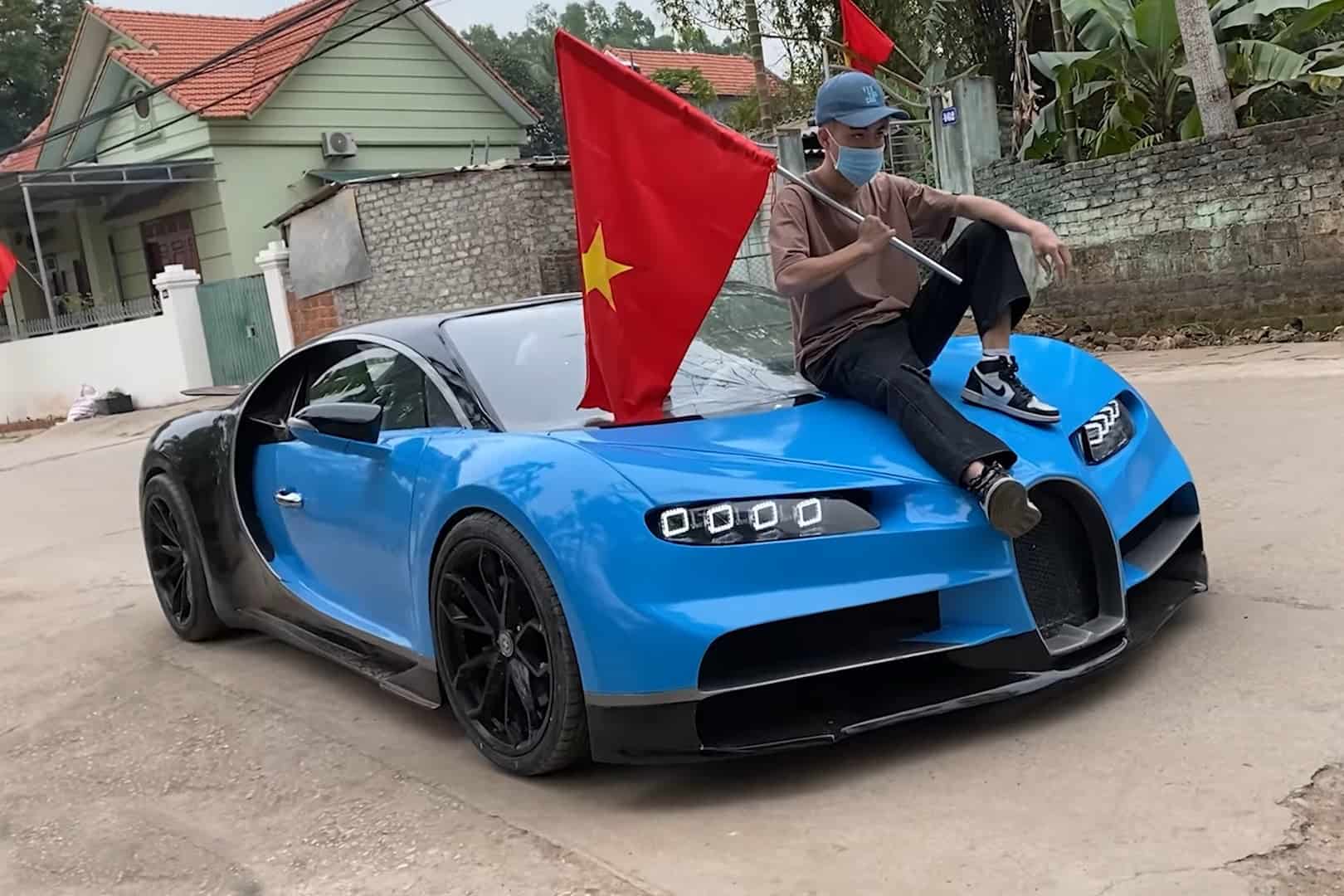 Jovem segurando a bandeira do Vietnã e sentado sobre a réplica do Bugatti Chiron
