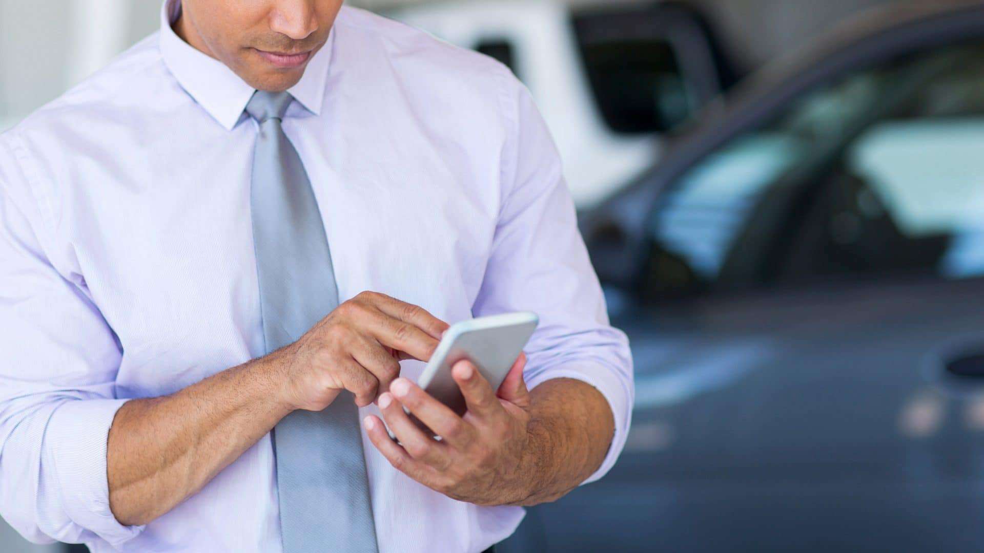 Homem usando um aplicativo de celular para fazer a transferência do veículo
