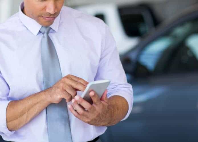 Homem usando um aplicativo de celular para fazer a transferência do veículo