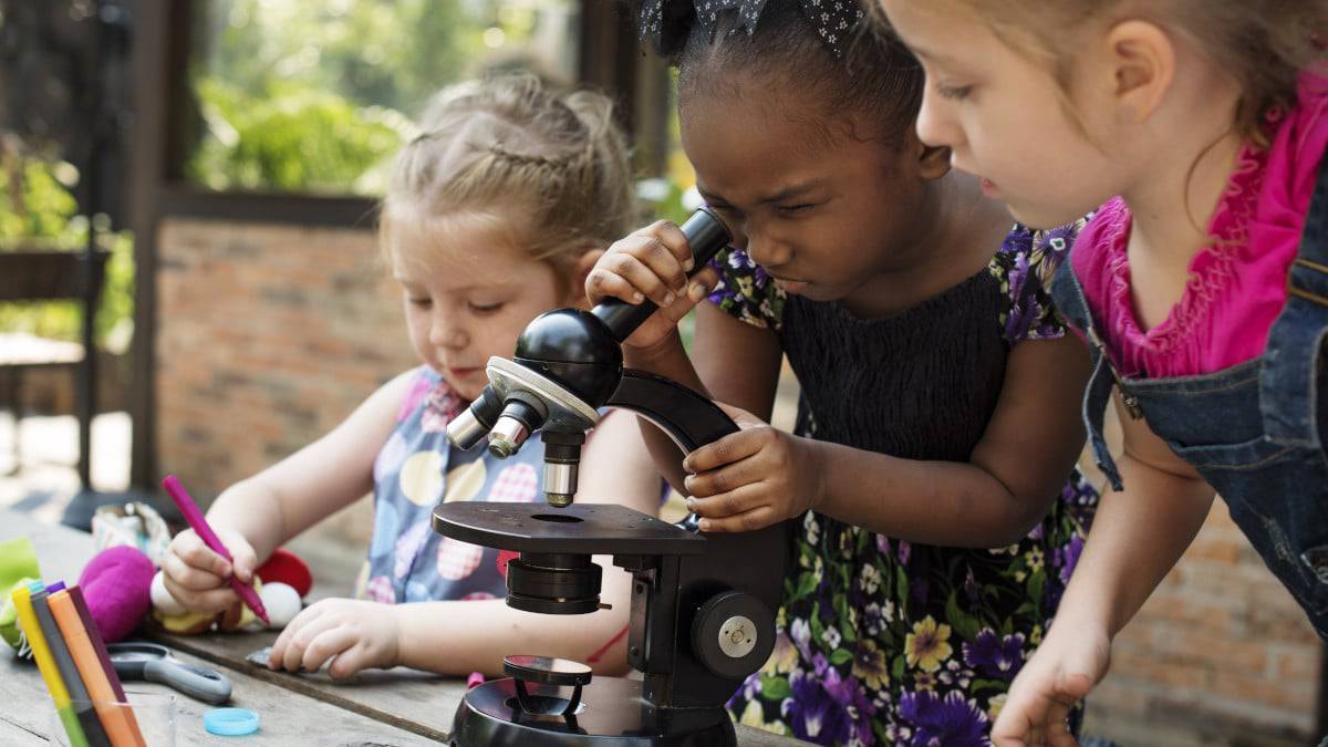 Garotas usando um microscópio e interessadas em ciência