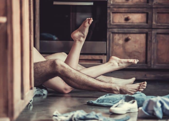 Homem e mulher com as pernas entrelaçadas no chão