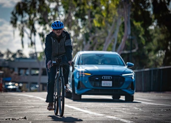 Veículo Audi e um ciclista na pista