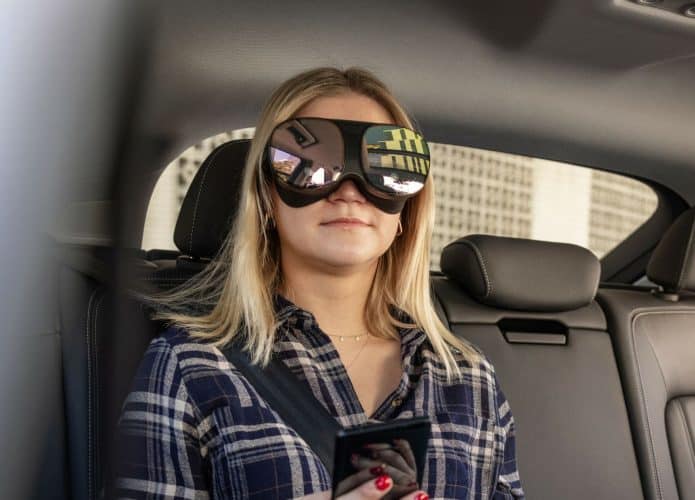 Mulher no banco de trás do veículo Audi com um headset de realidade virtual