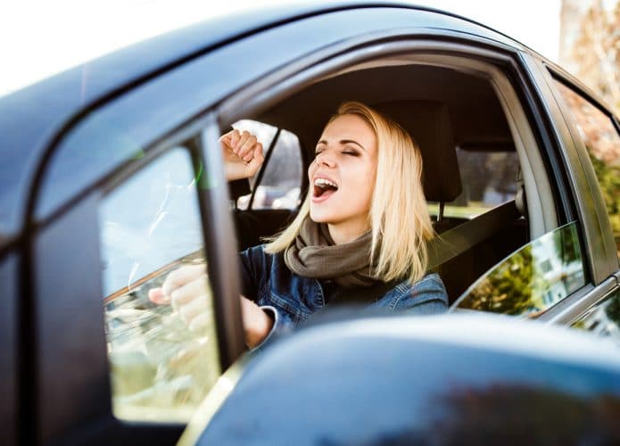 Motorista dentro de um veículo cantando, para ilustrar o uso do Modo Carro do Spotify