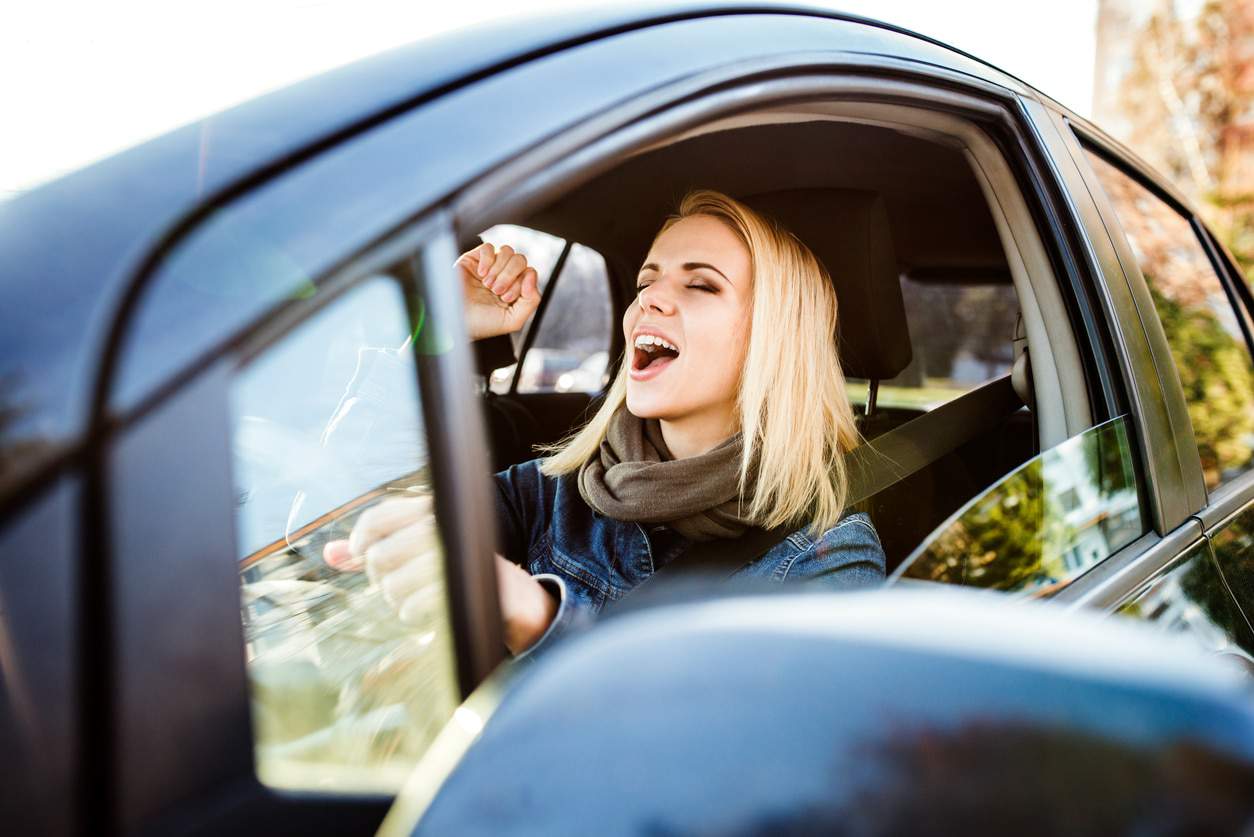 Motorista dentro de um veículo cantando, para ilustrar o uso do Modo Carro do Spotify